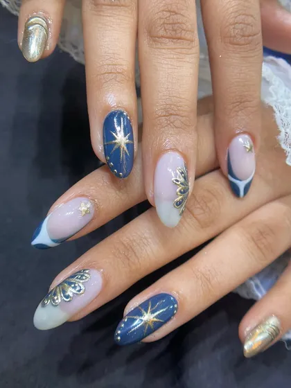 A beautiful combination of gel polish and hand-painted art on natural nails. The gold accents and starbursts are painted with precision for a stunning effect.