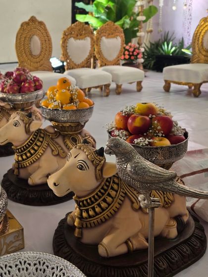 Another view of the decorated cow props, showing the detailed painting and the arrangement of apples and oranges.