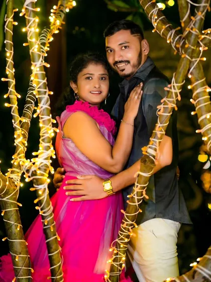 A close-up portrait of the couple amidst trees wrapped in fairy lights. The warm glow creates a beautiful and intimate atmosphere.