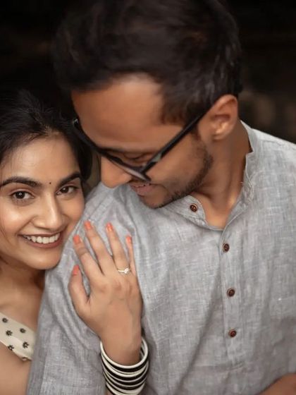 A cozy and intimate pre-wedding portrait. The groom's embrace from behind and the bride's happy smile make for a genuinely warm and loving photograph.