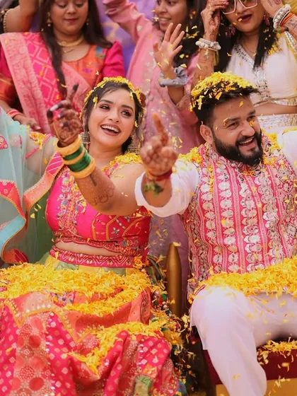 The couple seated and enjoying the flower shower during their Phoolon ki Holi. These are the candid, happy moments that make a wedding album special.