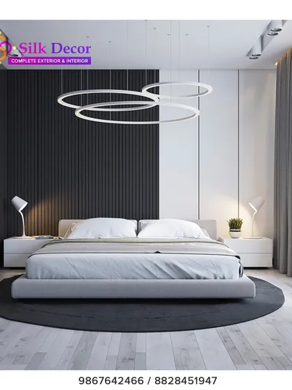 For clients who prefer a minimalist aesthetic, we design clean and contemporary pieces. This bedroom features one of our low-profile upholstered beds in a simple grey fabric, set against a striking black and white accent wall. The modern ring pendant lights complete the sleek, uncluttered look.