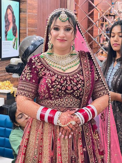 A candid shot of the bride in her full wedding attire. The rich velvet fabric and intricate embroidery are perfectly matched by the glamorous makeup and jewelry.