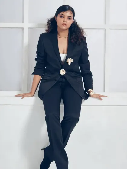A full-length shot displaying a powerful and chic look with a tailored black suit. The makeup is polished and clean, with defined features that photograph beautifully for commercial and corporate lifestyle shoots.
