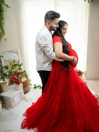 A tender embrace in our bright and airy studio. The vibrant red gown contrasts beautifully with the soft, light-filled setting, creating a portrait that is both passionate and pure.