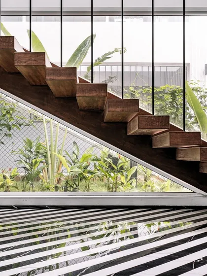 Detail is the language of luxury. This floating staircase at the Tellado home is a testament to that belief. I designed it with solid wood treads and sleek supports to create a sense of lightness, framing the lush greenery outside and complementing the bold, striped marble flooring.