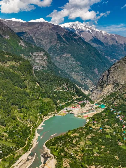 A stunning view of a valley in Himachal Pradesh, with a reservoir nestled between snow-dusted peaks. This is a perfect example of the link between man and nature.