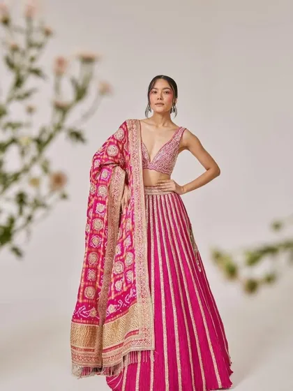 A model in a vibrant pink striped lehenga paired with a heavy Banarasi dupatta, creating a rich and festive look.