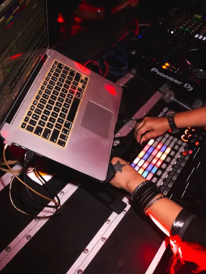 A close-up of my Ableton Live hybrid setup during a bass music night. You can see my hands on the APC40, triggering clips and effects in real-time. This is a powerful way to make your DJ sets more dynamic and unique.