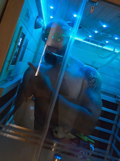 A client relaxes in our infrared sauna with the chromotherapy lights set to a calming blue. You can customize the lighting to match your mood, enhancing the mental benefits of your session.