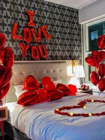 A classic and powerful statement for any romantic occasion. This hotel room setup features bold red "I Love You" foil balloons, heart-shaped balloon bouquets, and a heart on the bed made with LED candles for a safe and beautiful surprise.
