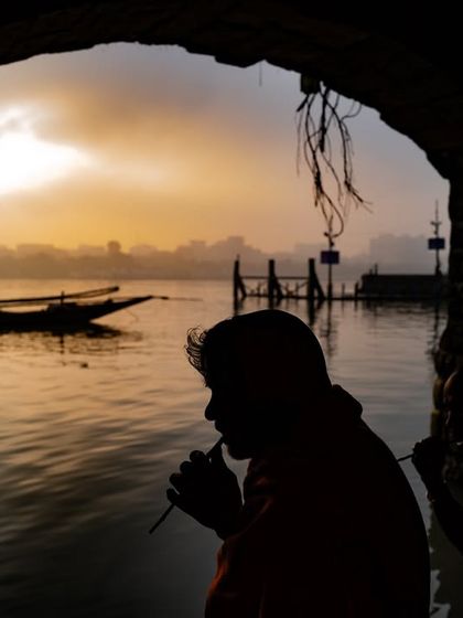 A silhouette of two people by the Hooghly river in Kolkata at sunrise, framed by an archway. A quiet, contemplative start to the day in the City of Joy.