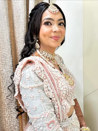 A close-up portrait in the off-white and pink handwork lehenga. The intricate details and soft colors are beautifully captured here.