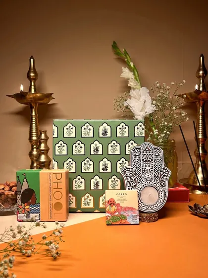 This eco-chic Diwali hamper features a beautiful green floral box, a Hamsa hand candle holder, and organic incense, making it a thoughtful and sustainable gift.