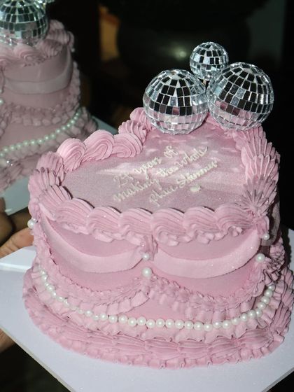 Serving sparkle and sweetness with this disco-themed vintage cake. The pink frills, edible pearls, and shiny disco balls are perfect for making the whole place shimmer.