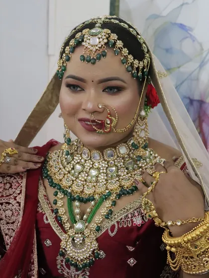 The bride adjusting her jewellery, a candid moment that shows off her complete look, including the heavy kundan necklace and matha patti.