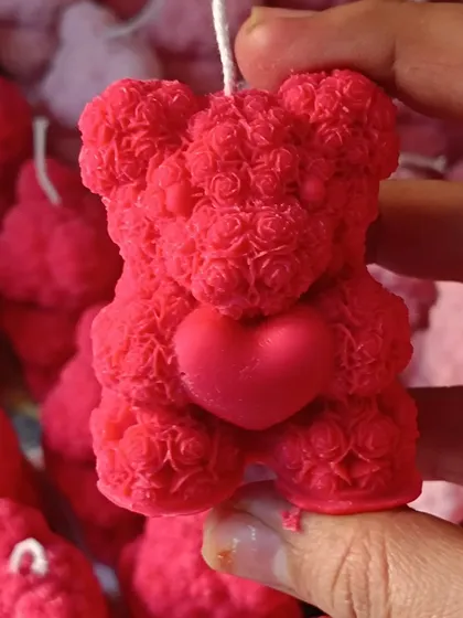 A close-up of a single red rose-textured teddy bear candle.
