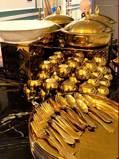 A close-up of our gleaming golden cutlery and serving dishes. We allow you to craft an event more stunning than you've ever imagined, with every detail delivered with elegance and ease.