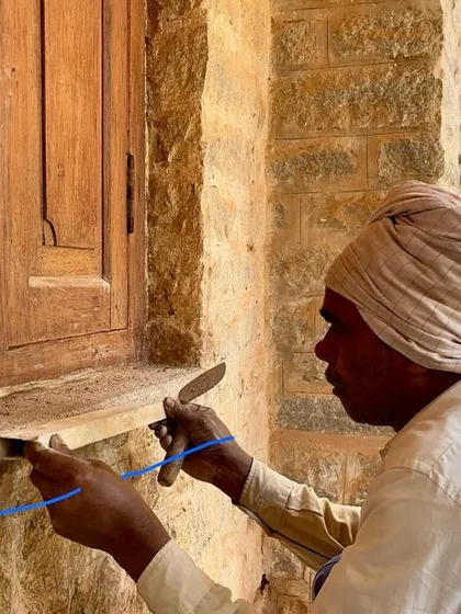 A repeat image of a craftsman finishing the mortar around a window, underscoring the importance of this final sealing step.