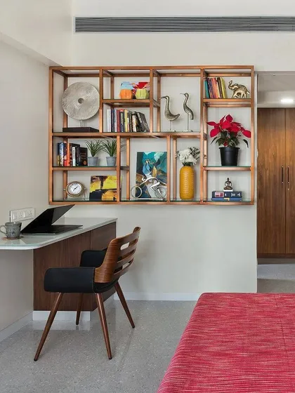 This bedroom corner was designed to be a compact and stylish workspace. The floating desk saves floor space, while the open wooden shelving unit provides ample room for books and decor without feeling heavy.