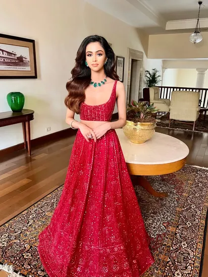A full-length view of another stunning red creation by Sawan Gandhi, styled with an elegant emerald necklace for a sophisticated evening look.
