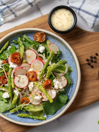 A beautiful and healthy salad featuring asparagus, radish, cherry tomatoes, and feta cheese. It's a perfect side dish or a light main course for a health-conscious crowd.