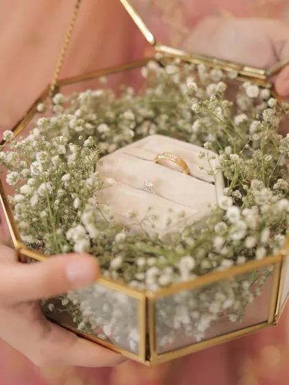 A delicate ring platter, with the rings nestled in a bed of baby's breath inside a gold and glass hexagonal box. A beautiful way to present the symbols of your commitment.
