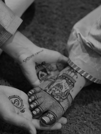 A creative shot showing the bride's feet mehandi held in the groom's hands. This black and white photo beautifully captures the intricate details and the love between the couple.