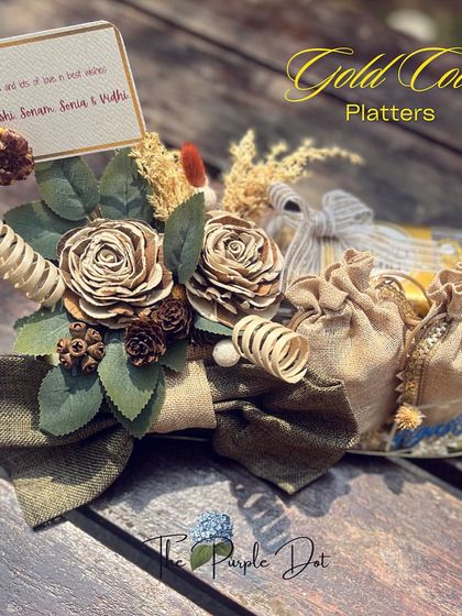 This gold coin platter, designed for a baby boy's arrival, features rustic elements like burlap pouches and sola wood flowers, offering a sophisticated and traditional gifting option.