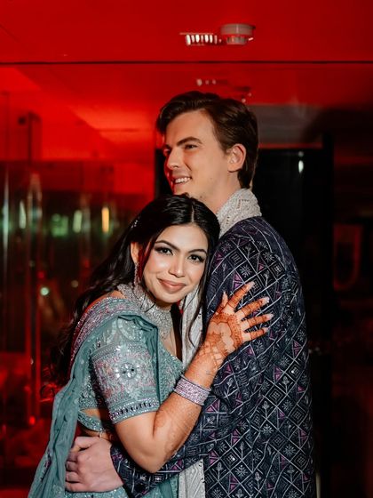 An intimate moment amidst the vibrant party. The dramatic red lighting adds a touch of glamour and romance to this candid couple portrait.