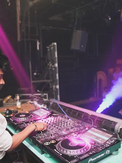 DJing at Freq Club under purple lights with smoke effects in the background.