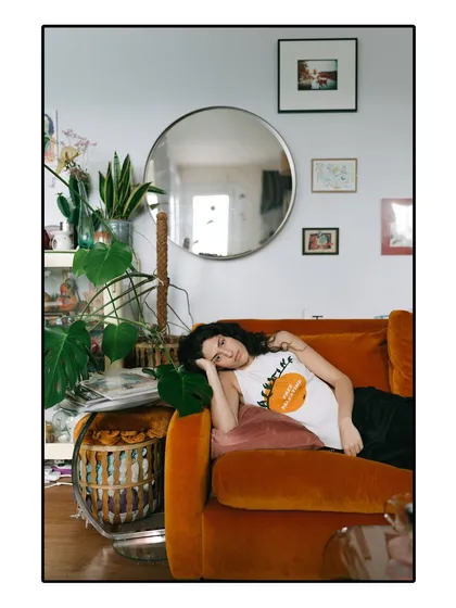 A relaxed lifestyle shot of Riya Miam on her couch, surrounded by plants and personal decor that reflect her personality.