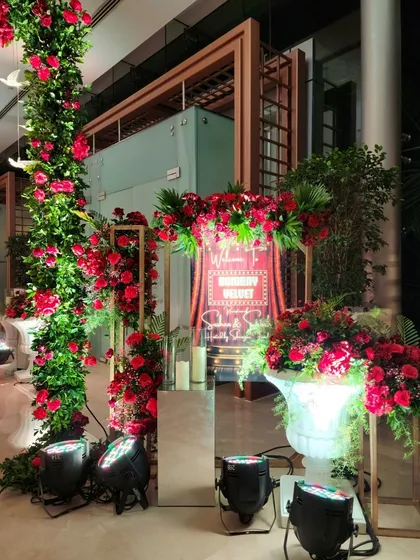 A detailed view of the welcome area, featuring a neon sign, mirrored pedestals, and arrangements of red roses in classic white urns. Every detail is curated to create a luxurious feel.