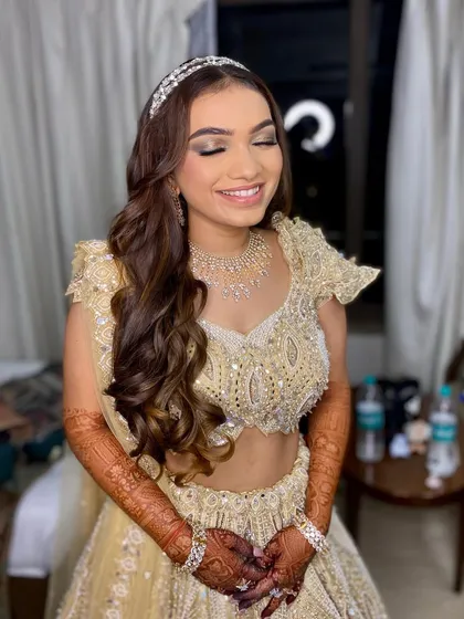 Khushbu sparkling on her Sangeet night. Her makeup features a classic smokey eye and a nude lip, paired with soft curls for a romantic and glamorous look.