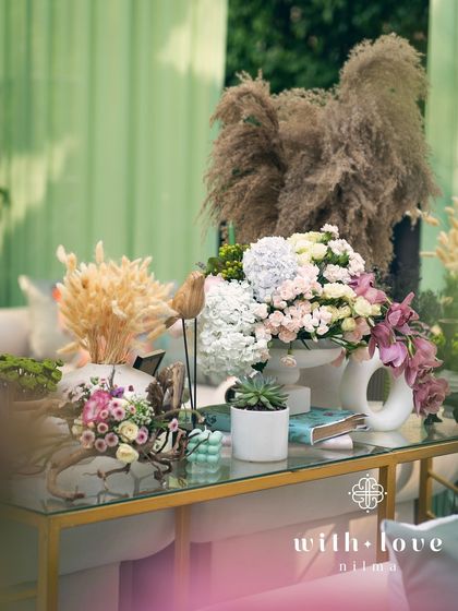 A console table with floral arrangements and pampas grass, adding to the layered and textured decor of the baby shower.