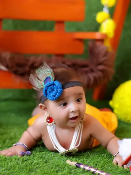 Tummy time poses are great for babies who are a few months old. This little one, dressed as Krishna, shows a curious expression during a playful moment on the grass mat.