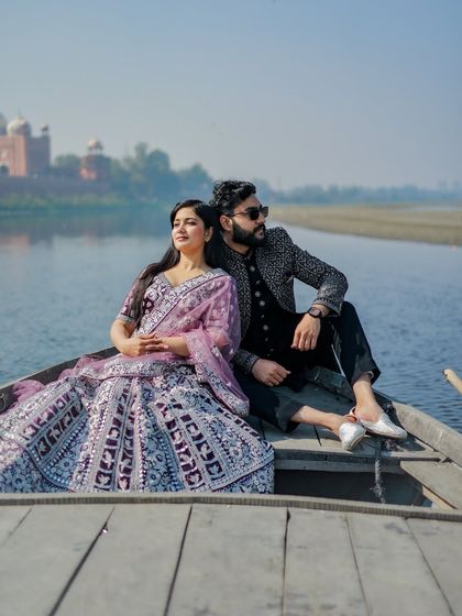 Another perspective from the Yamuna, this shot captures the couple in their ornate outfits, looking like royalty as they float by the Taj Mahal.