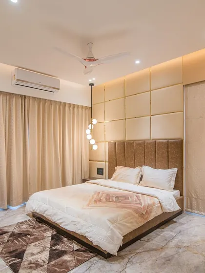 Another angle of the bedroom with the tufted wall panel, highlighting the room's spaciousness and clean lines. The geometric rug adds texture and visual interest to the marble flooring.