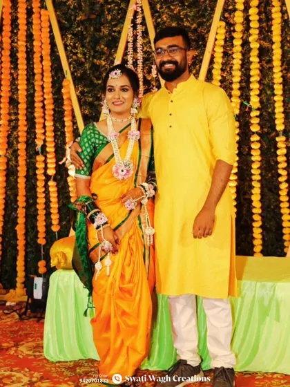 A beautiful portrait of a Haldi bride and groom. Her jewellery, made with delicate pink flowers and mogra buds, perfectly complements her traditional orange and green saree.