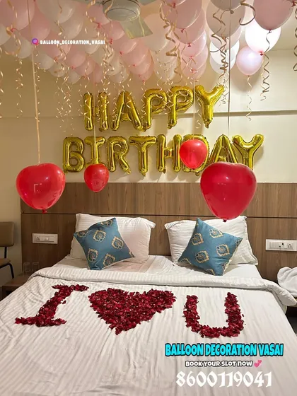 A romantic birthday surprise featuring "Happy Birthday" and "I ❤️ U" messages. The bed is decorated with a rose petal heart, and pink and white balloons float above.