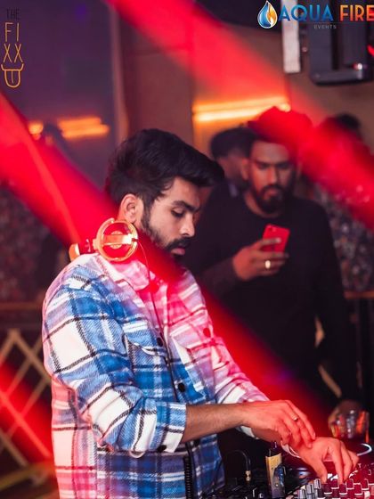 A focused shot of me mixing at The Fixx Bar, with my signature gold headphones and a stylish flannel shirt.