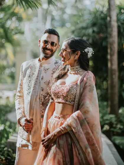 Fun and stylish for their Bali sangeet. The bride's floral Sabyasachi lehenga is paired with cool sunglasses, and the groom's embroidered sherwani is effortlessly chic.