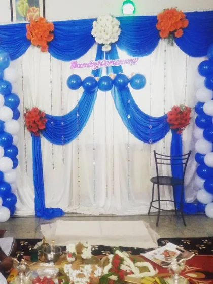 This is a budget-friendly naming ceremony decoration using blue and white drapes and balloon pillars. It provides a simple yet elegant backdrop for the function.