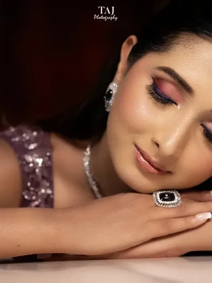 A close-up beauty shot of a bride, highlighting her flawless makeup and the intricate details of her jewelry. The tattoo on her arm adds a personal touch.