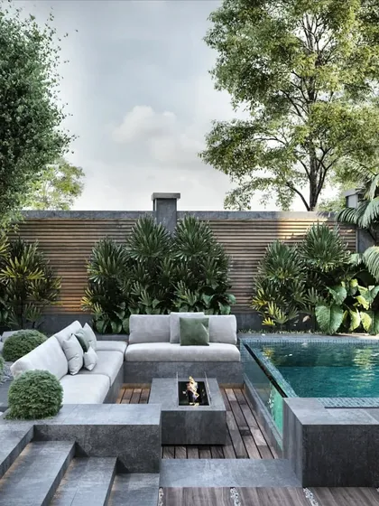 A luxurious poolside retreat designed for ultimate relaxation. This landscape plan features a modern fire pit, comfortable all-weather sofas, and lush, layered planting that provides privacy and a tropical feel. The combination of stone, wood, water, and fire creates a balanced and sophisticated outdoor lounge.