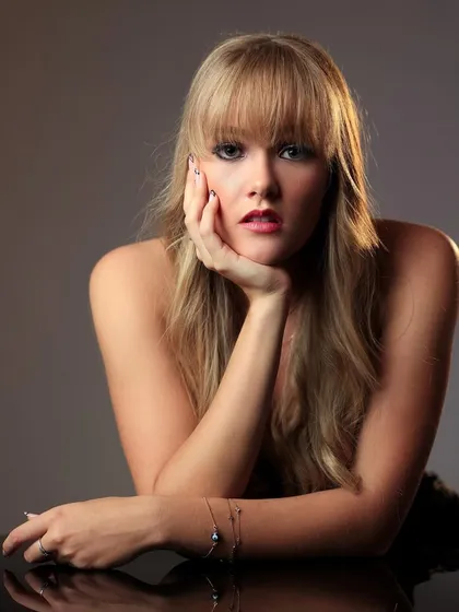 A classic headshot pose, with the model resting her chin on her hand.