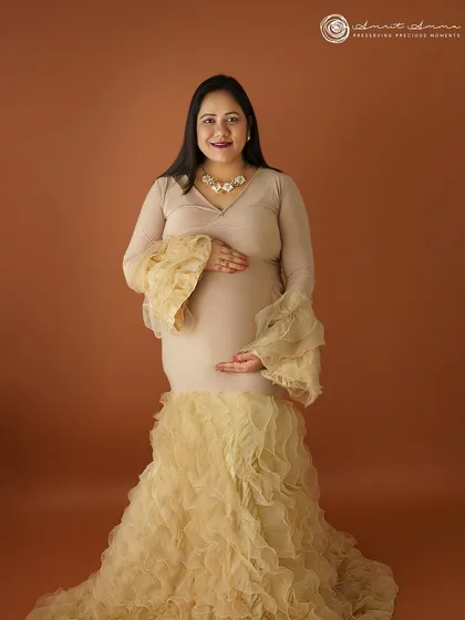 A beautiful solo portrait in a ruffled champagne gown. The warm, earthy backdrop complements the dress perfectly, creating a sophisticated and elegant look.