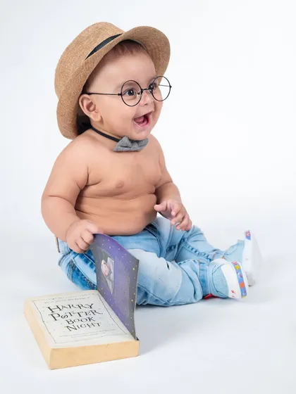 A happy little wizard with his book of spells. The simple white background puts all the focus on his adorable Harry Potter costume.