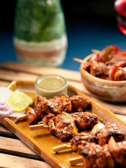 A platter of Murg Adani Boti served with fresh lemon, onions, and a side of mint chutney. This is a classic appetizer that I prepare with the freshest chicken.