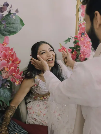 A playful, candid moment where the groom gently touches the bride's face, making her laugh. It's these simple, loving gestures that we cherish.